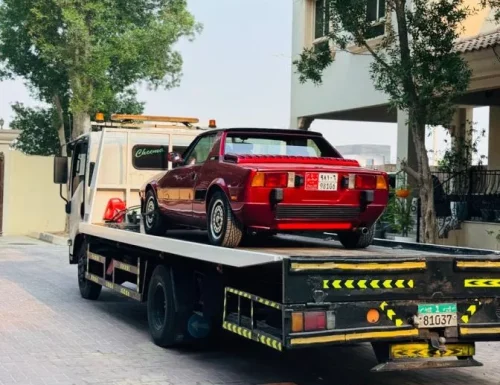 Red car on flatbed tow truck in residential setting