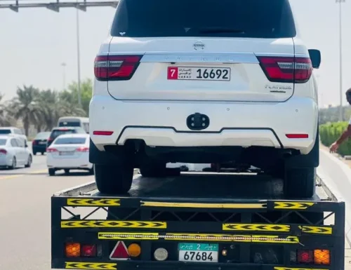 White car on a flatbed truck with highway signs