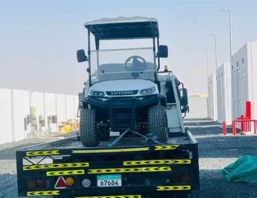 Utility vehicle on a flatbed truck in a gravel area.