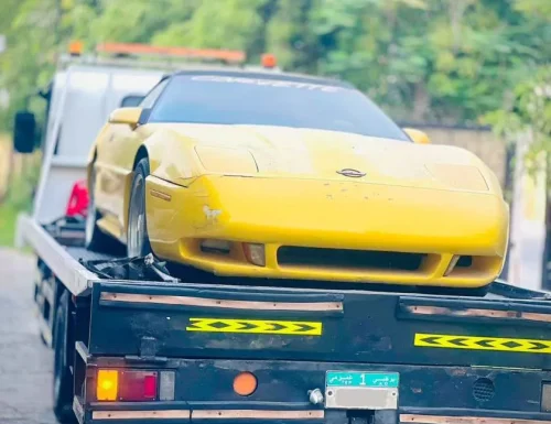 A yellow Chevrolet Corvette sports car being safely transported on a flatbed recovery truck by Perfection Car Recovery in Abu Dhabi.